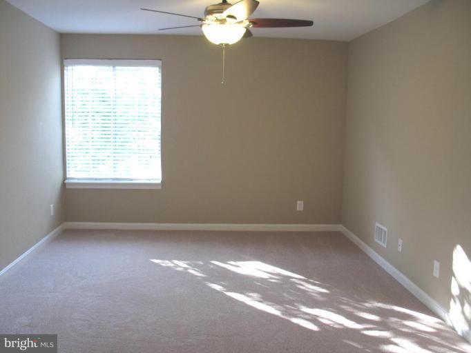 4932 Columbia Road, Unit 7 Columbia, MD 21044 - Photo 7 of 19 en empty room with windows and chandelier fan