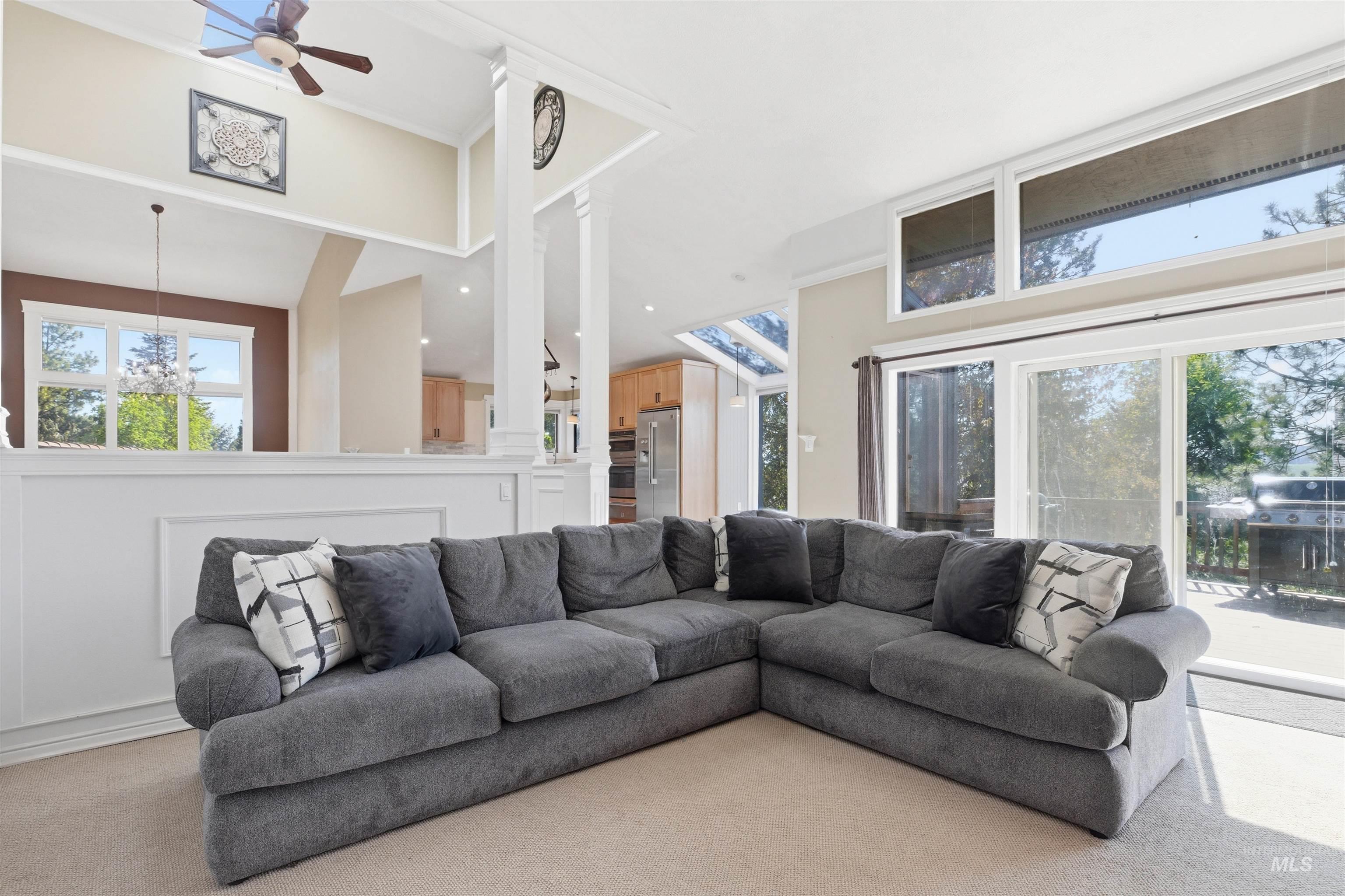 1540 Pine Cone Road Moscow, ID 83843 - Photo 14 of 49 Living area featuring a vaulted ceiling with a ceiling fan, a partial wall with wainscoting, and carpeted flooring