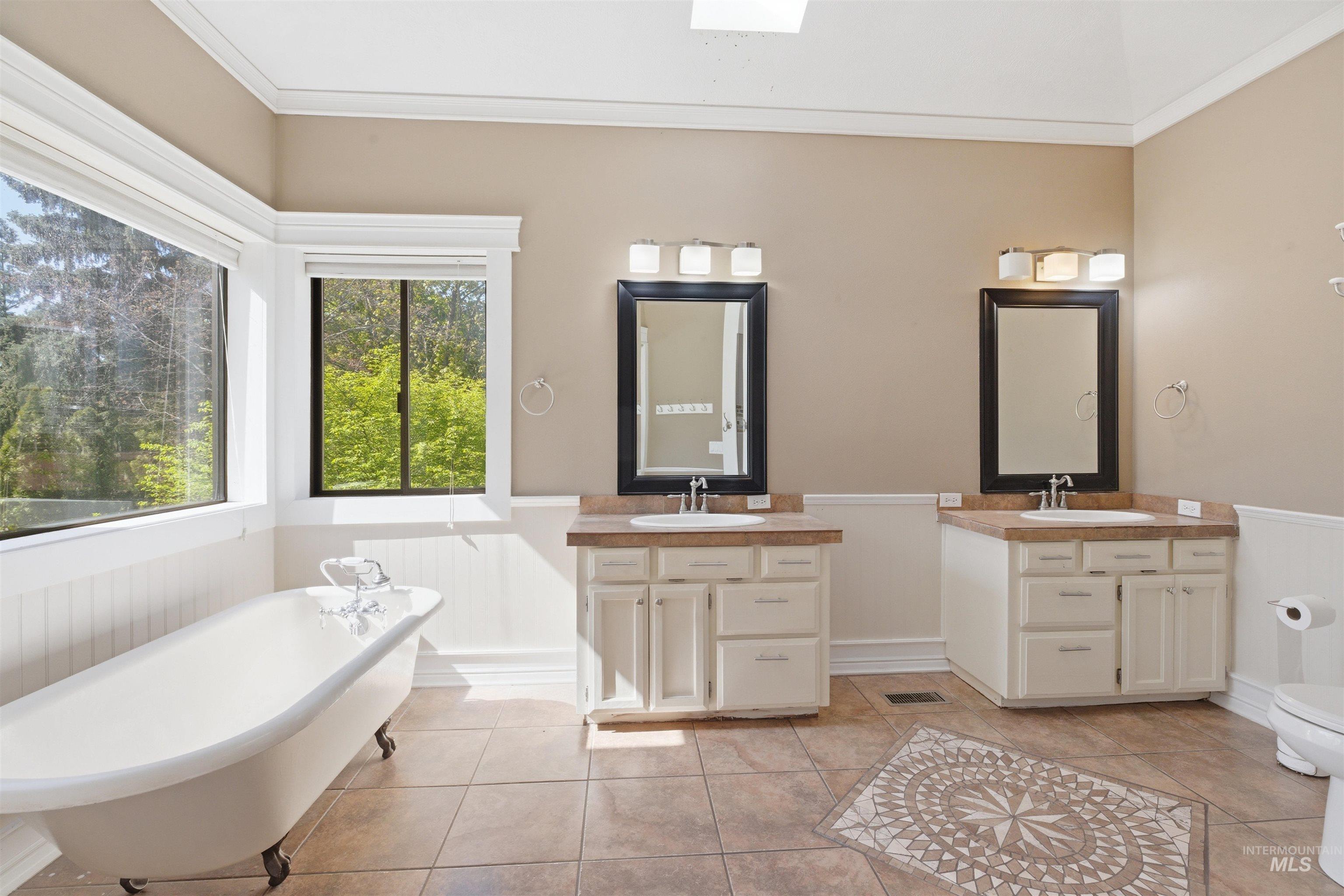 1540 Pine Cone Road Moscow, ID 83843 - Photo 17 of 49 Expansive bathroom featuring a white clawfoot tub, dual vanities with integrated sinks, and neutral tile flooring with an inlaid mosaic design