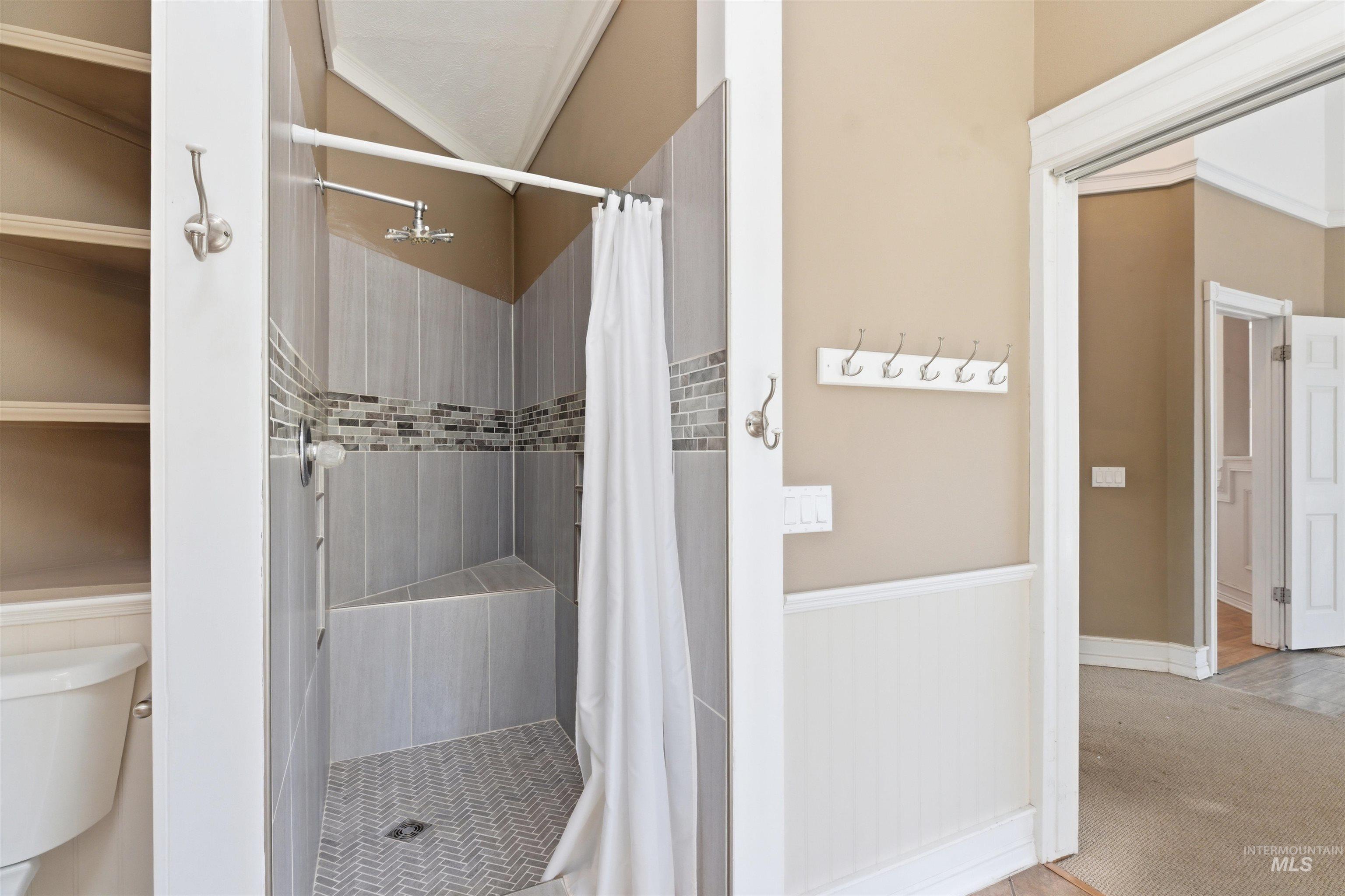 1540 Pine Cone Road Moscow, ID 83843 - Photo 19 of 49 Tiled shower with a built-in bench, chevron-patterned floor, and a mosaic accent band