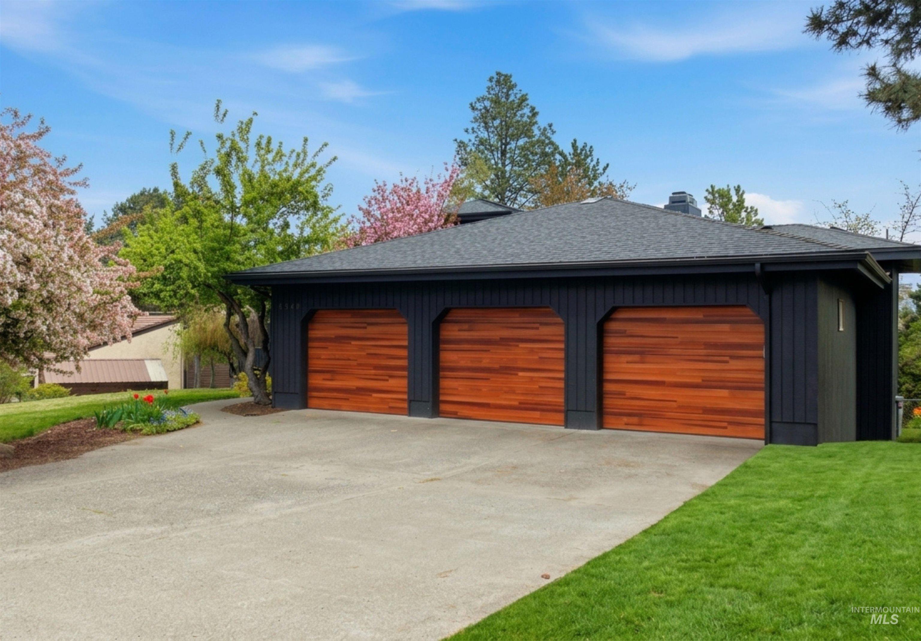 1540 Pine Cone Road Moscow, ID 83843 - Photo 2 of 49 Three-car garage featuring rich wood-finish doors and dark exterior siding