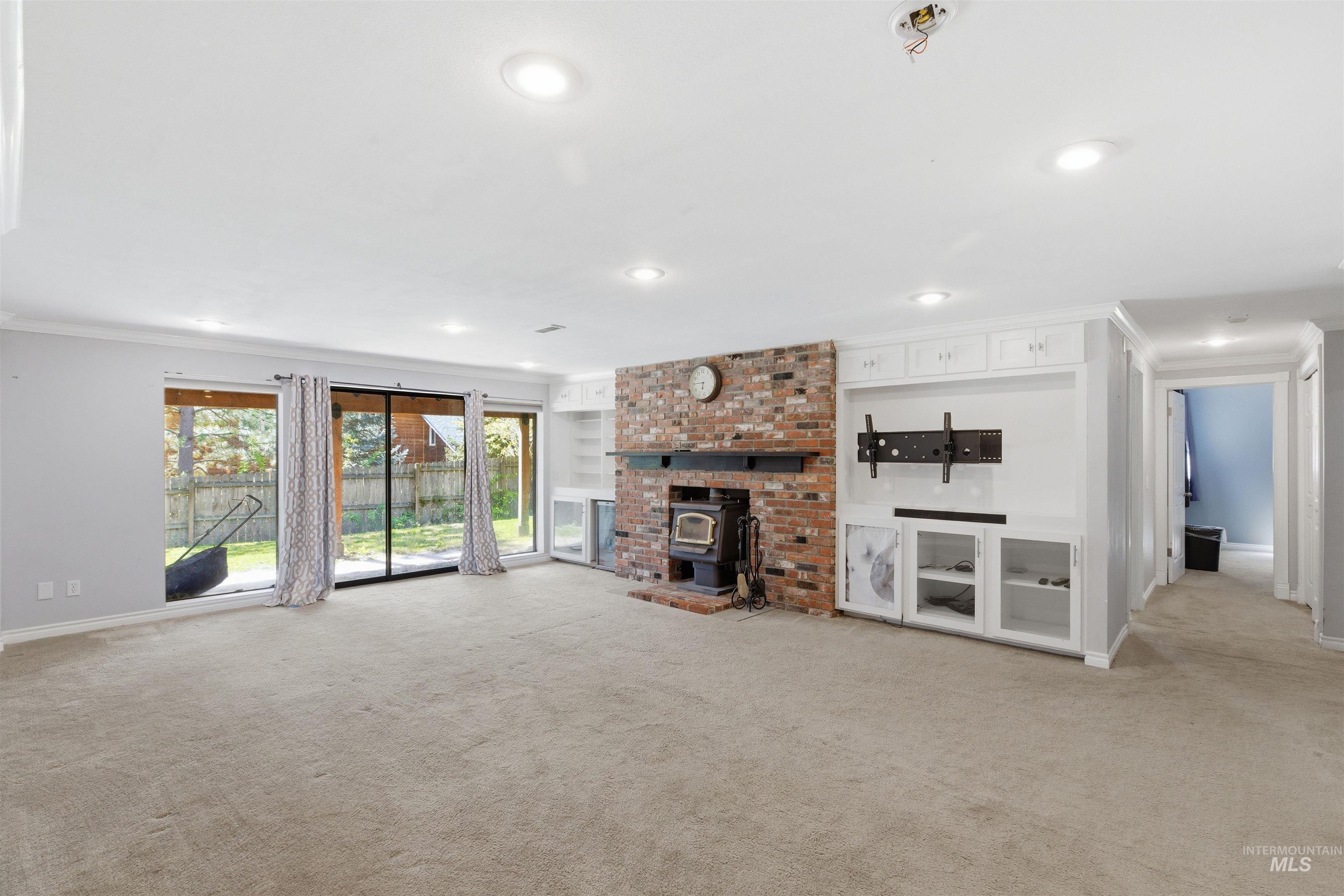 1540 Pine Cone Road Moscow, ID 83843 - Photo 30 of 49 Expansive living area featuring a brick-clad fireplace with a wood-burning stove insert, built-in white cabinetry, recessed lighting, and sliding glass doors