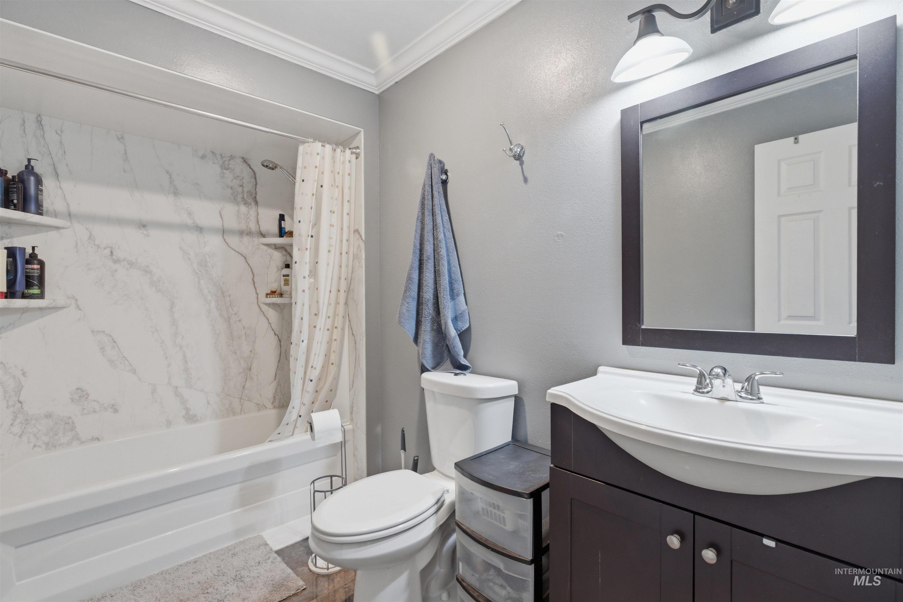 1540 Pine Cone Road Moscow, ID 83843 - Photo 31 of 49 Bathroom featuring a shower-tub combination with a white marble-patterned surround, a dark wood-finish vanity with an integrated white sink, a framed mirror, and a wall-mounted light fixture