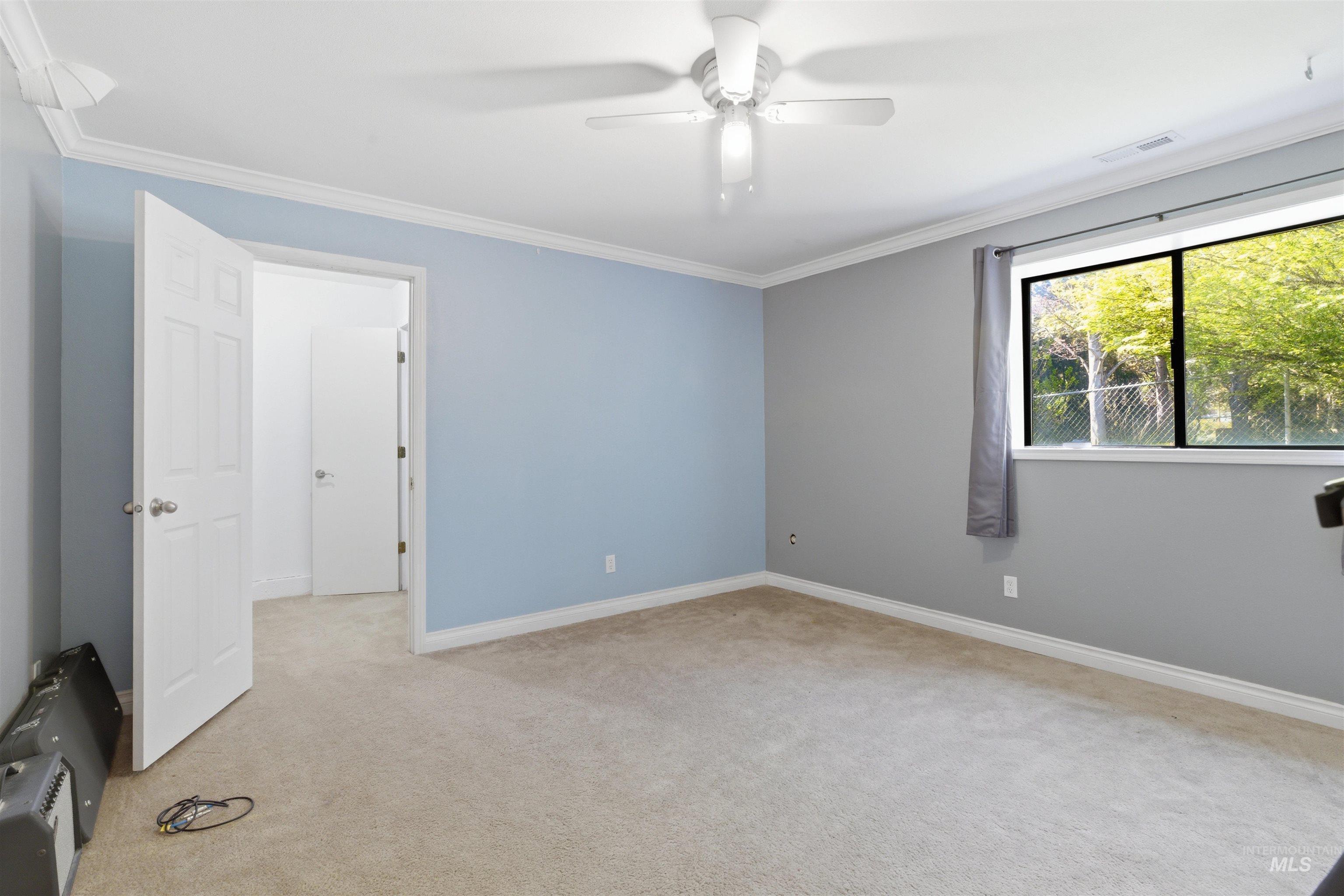 1540 Pine Cone Road Moscow, ID 83843 - Photo 32 of 49 Carpeted room with crown molding, a ceiling fan, and a window with a green outdoor backdrop