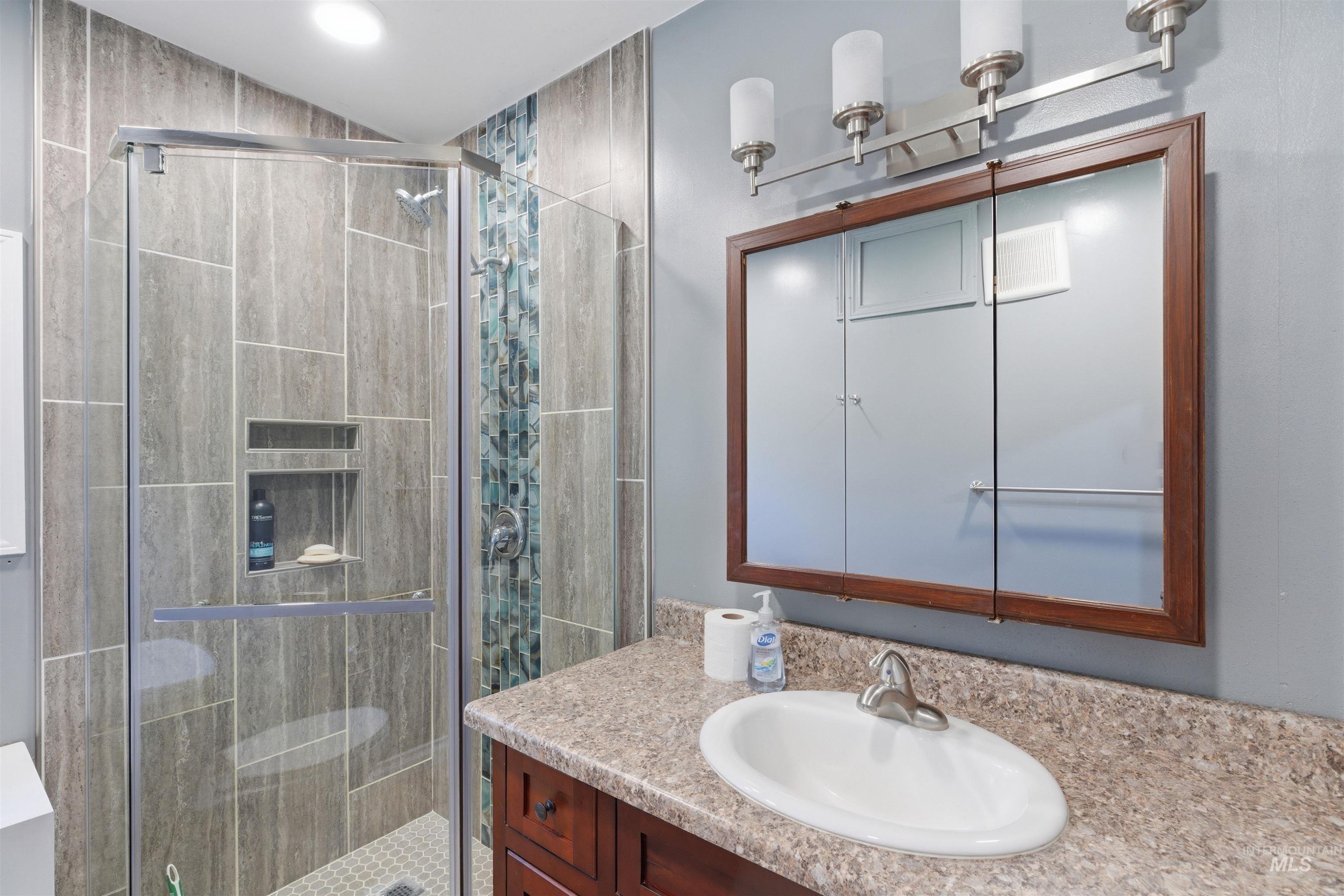 1540 Pine Cone Road Moscow, ID 83843 - Photo 34 of 49 Modern bathroom featuring a glass-enclosed shower with large format tile, a decorative mosaic tile accent, and an integrated shower niche