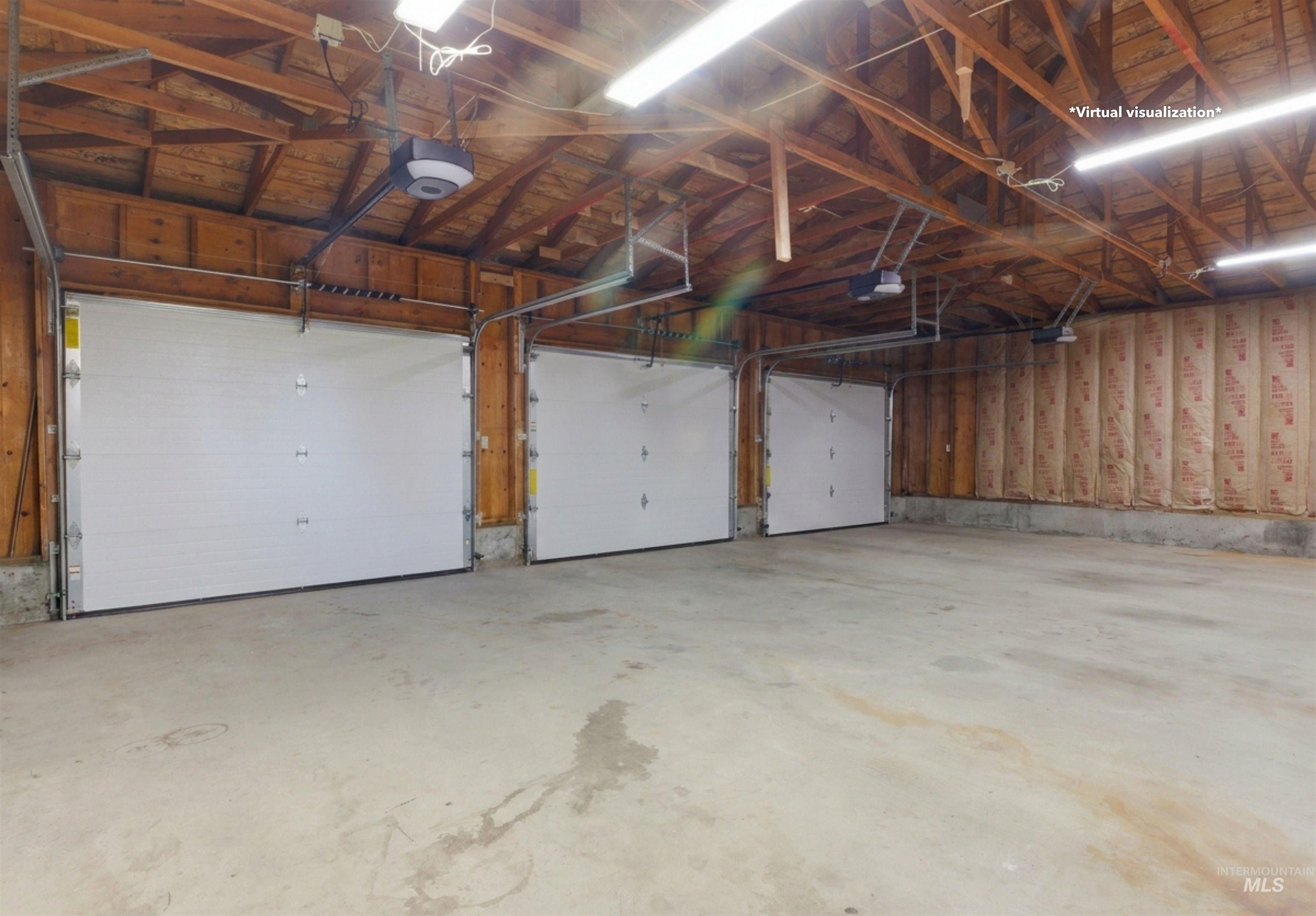 1540 Pine Cone Road Moscow, ID 83843 - Photo 36 of 49 Spacious garage featuring three individual overhead doors with automatic openers, exposed wood beam ceiling, concrete flooring, and wall insulation