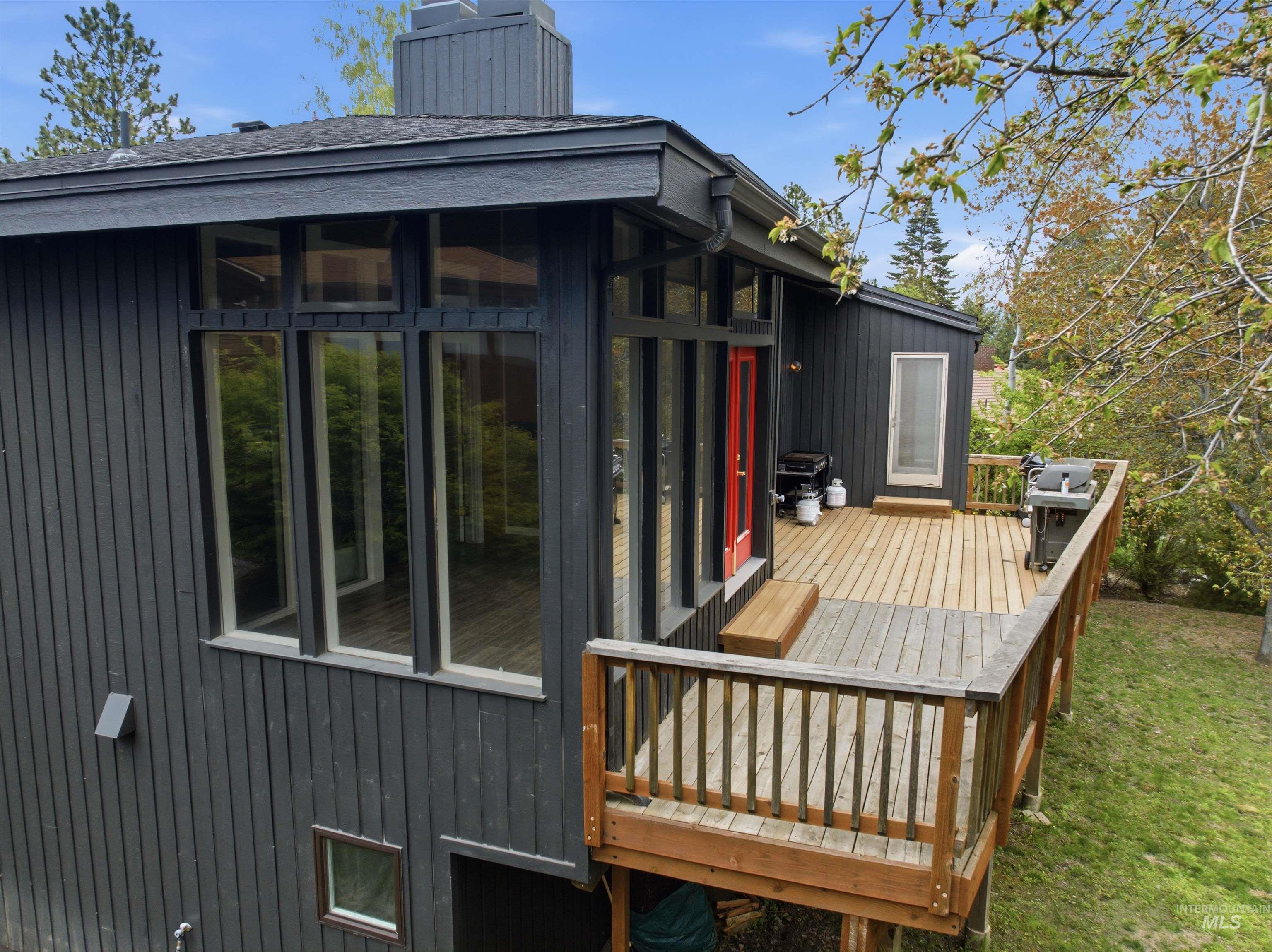 1540 Pine Cone Road Moscow, ID 83843 - Photo 40 of 49 Multi-level wood deck extending from the structure, featuring vertical wood plank siding and a prominent red entry door