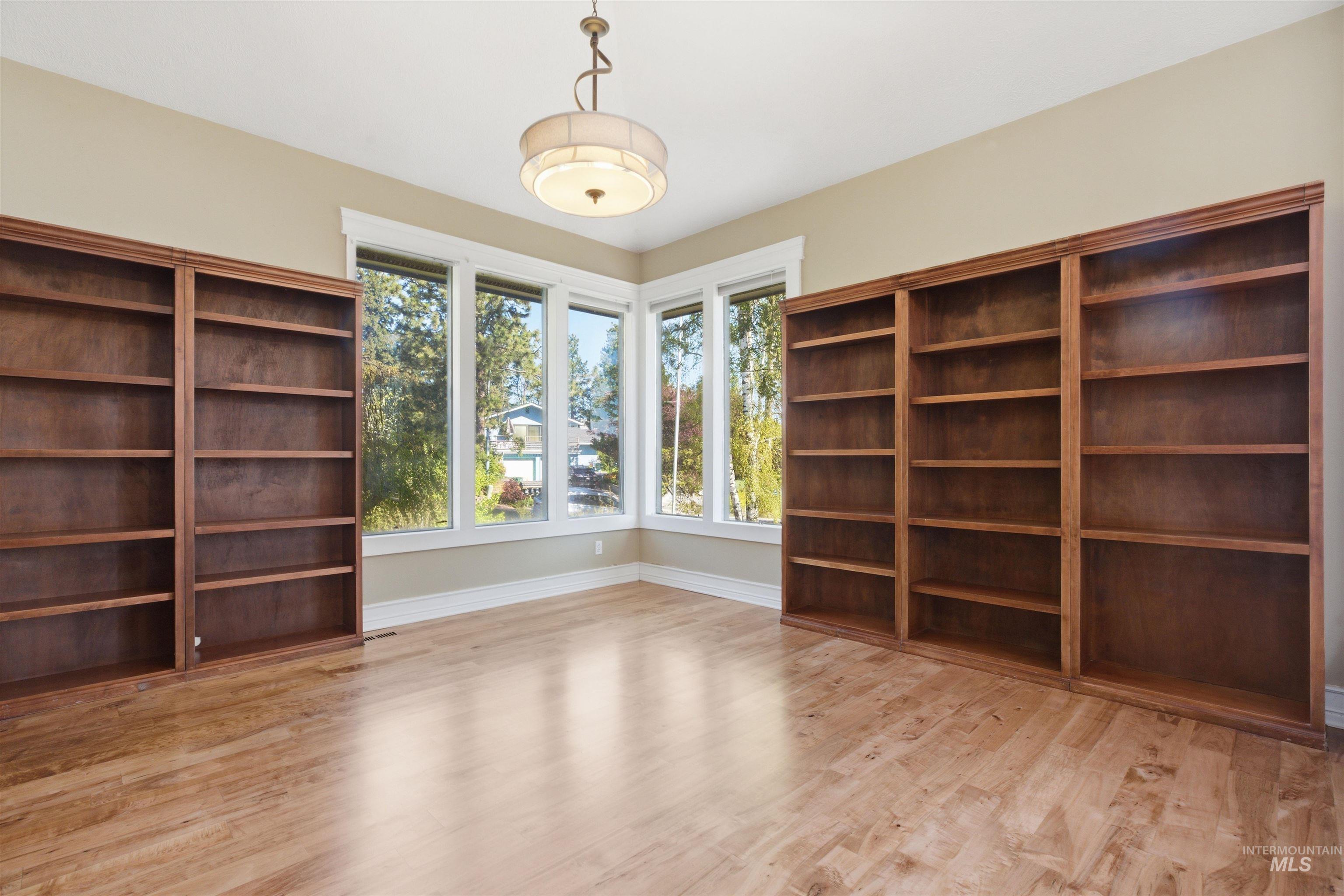 1540 Pine Cone Road Moscow, ID 83843 - Photo 4 of 49 Room featuring built-in wood shelving units, multiple windows, wood-finish flooring, and a central ceiling light fixture