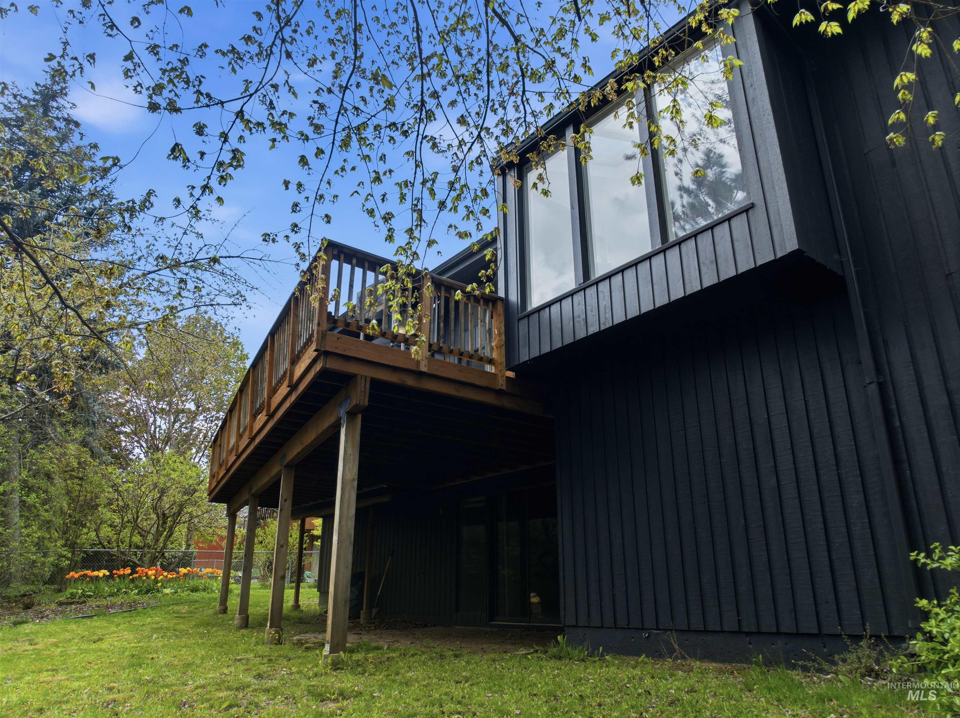 1540 Pine Cone Road Moscow, ID 83843 - Photo 41 of 49 Modern black vertical siding exterior with a wood deck, large upper-level windows, and a grassy yard