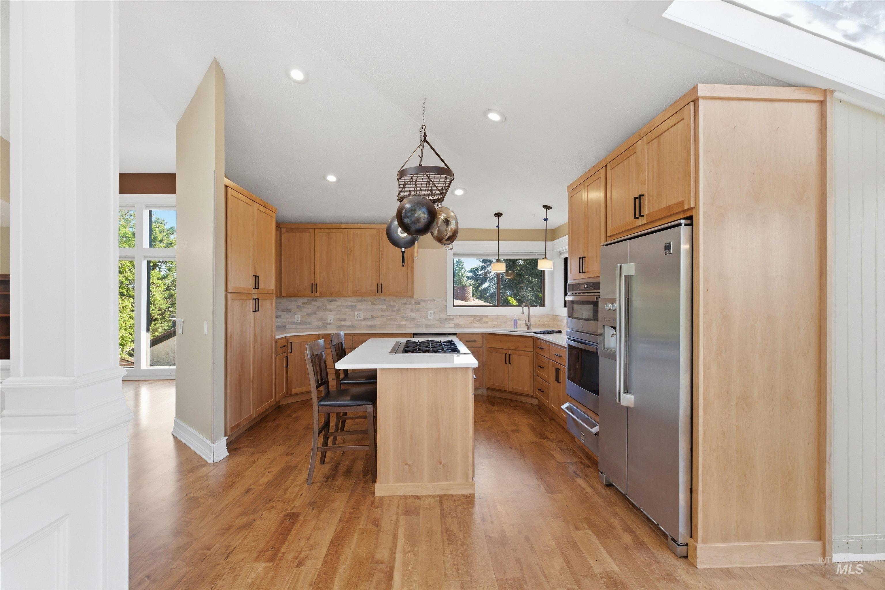 1540 Pine Cone Road Moscow, ID 83843 - Photo 8 of 49 Kitchen featuring light wood-finish cabinetry, stainless steel appliances, a center island with countertop seating, and recessed lighting