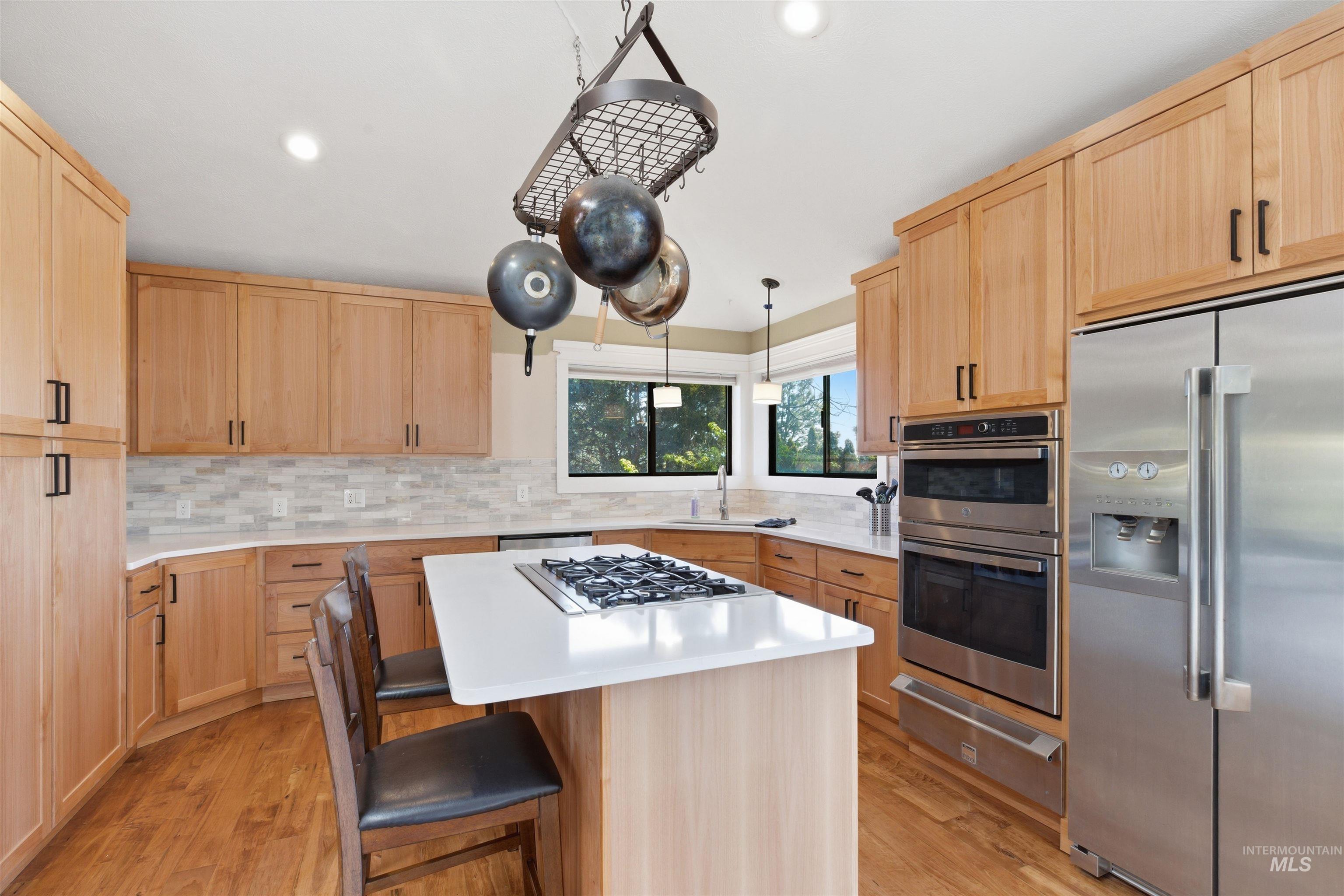 1540 Pine Cone Road Moscow, ID 83843 - Photo 10 of 49 Kitchen featuring light wood cabinetry, stainless steel appliances, a center island with a gas cooktop, white countertops, and wood-finish flooring
