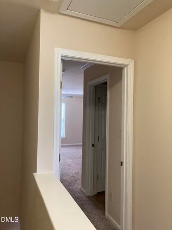 a view of a hallway with wooden floor and a bathroom