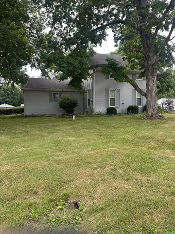 a view of a house with a yard and a large tree