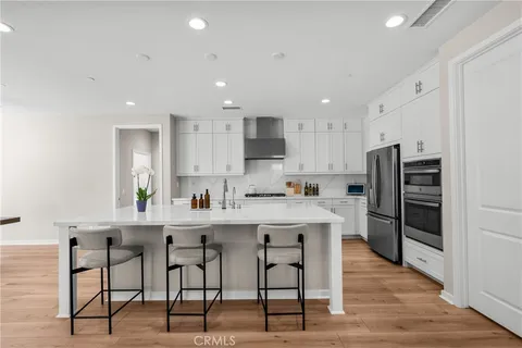 a kitchen with stainless steel appliances kitchen island granite countertop a stove a refrigerator and a dining table with wooden floor