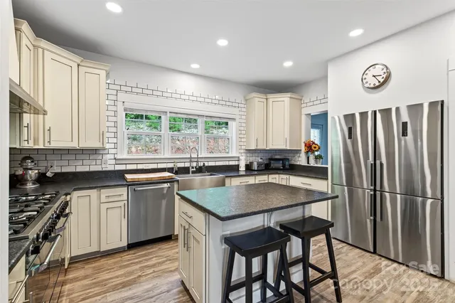 a kitchen with stainless steel appliances granite countertop a stove a sink dishwasher and a refrigerator with wooden floor