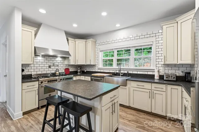 a kitchen with granite countertop a sink stove cabinets and wooden floor