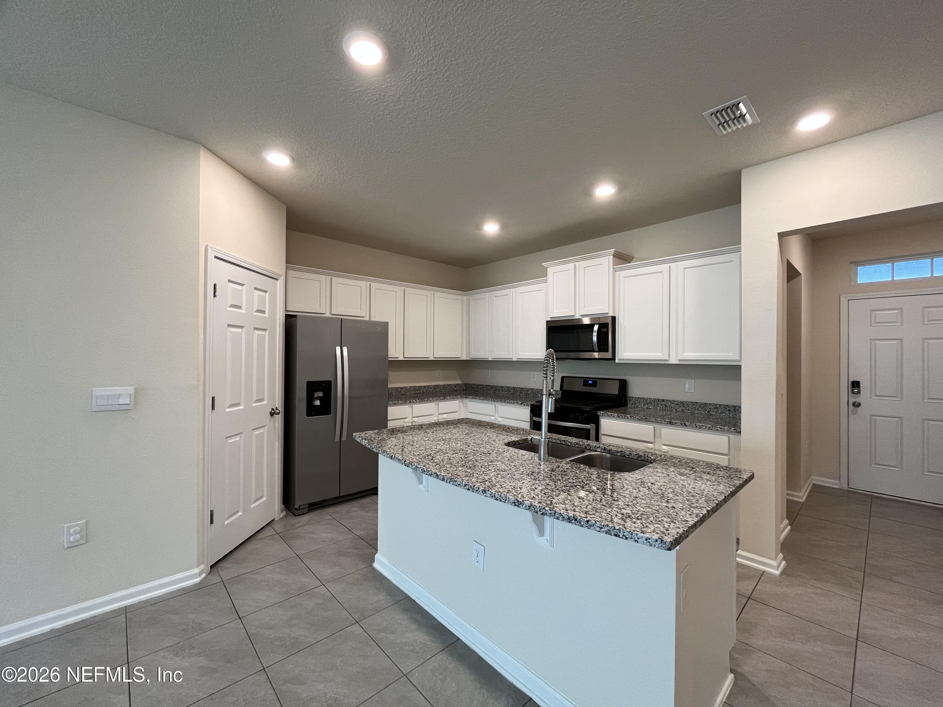 548 Coastline Way St. Augustine, FL 32092 - Photo 6 of 21 a kitchen with stainless steel appliances granite countertop refrigerator sink and cabinets