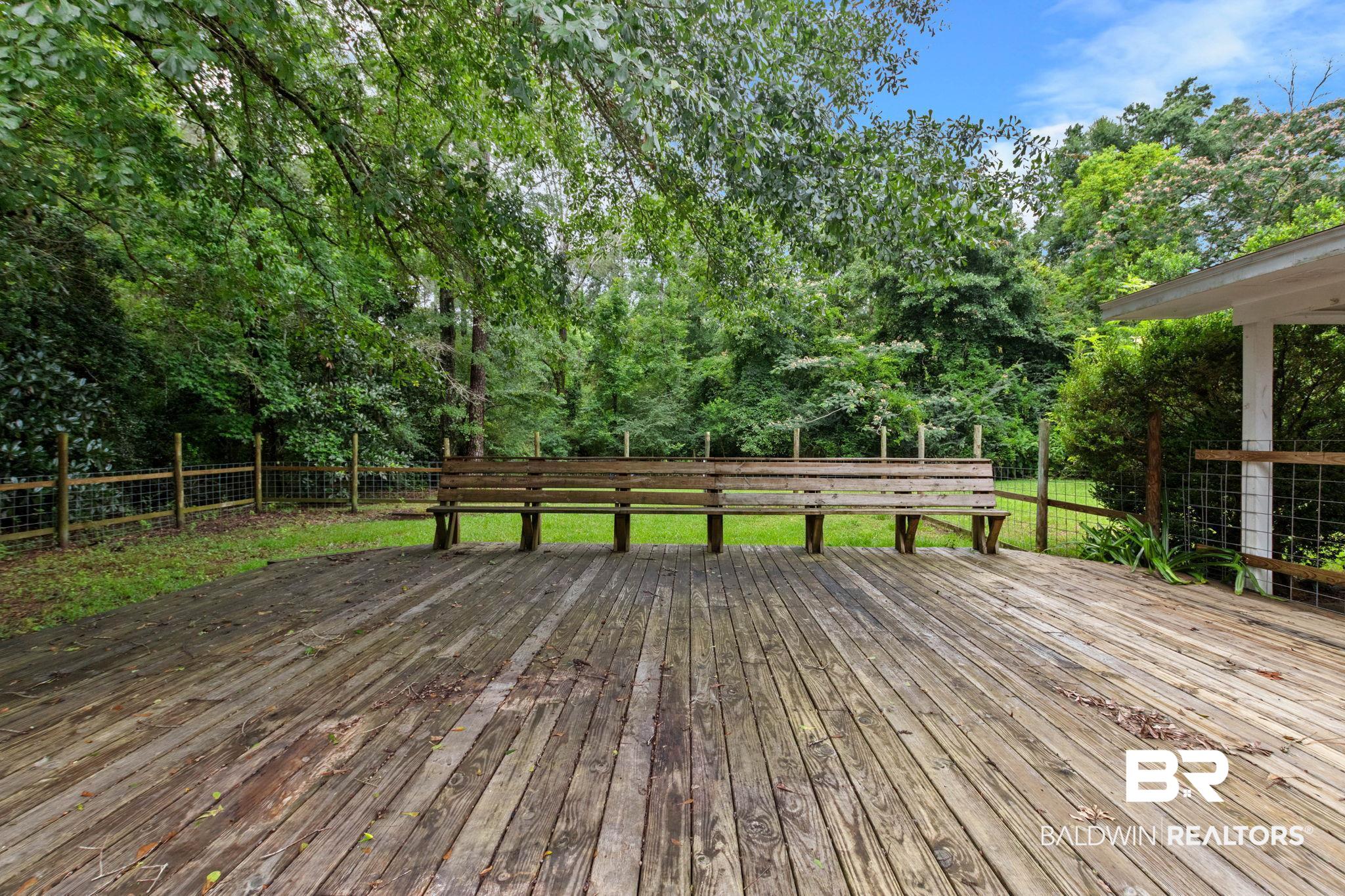 384 Old Bratt Road Atmore, AL 36502 - Photo 61 of 64 Spacious wood deck with a built-in wooden bench, surrounded by mature trees and a wire-mesh fence