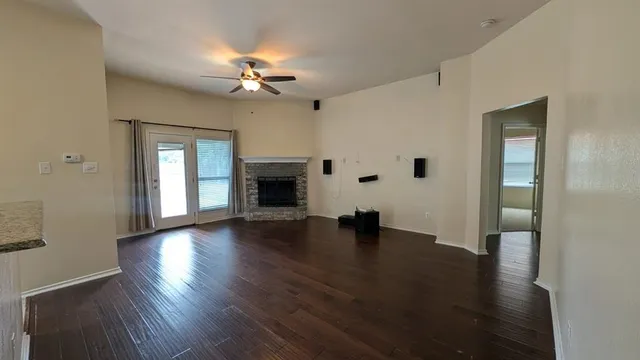 a view of an empty room with wooden floor fireplace and a window