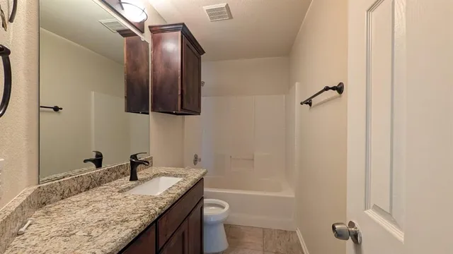 a bathroom with a granite countertop sink toilet and shower