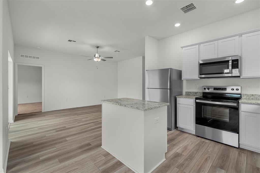 13352 Tula Loop Astatula, FL 34705 - Photo 5 of 19 a kitchen with stainless steel appliances granite countertop a refrigerator stove and microwave