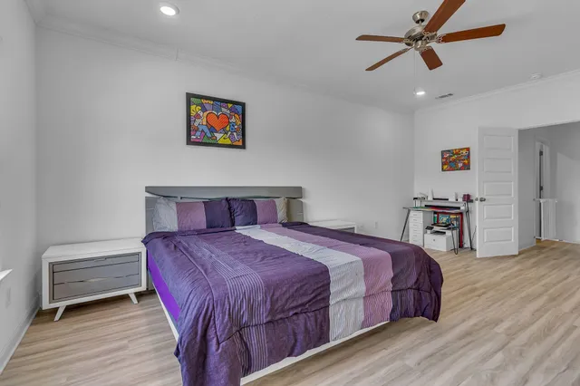 a bedroom with a bed a dresser and wooden floor