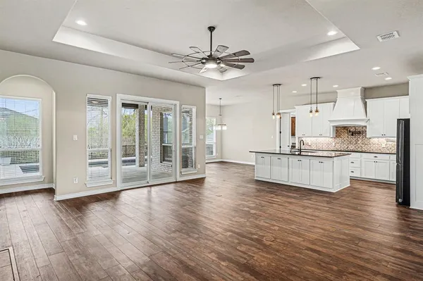 a view of a livingroom with a chandelier fan and wooden floor
