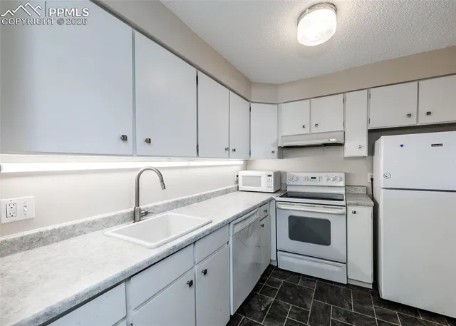 a kitchen with granite countertop white cabinets and white appliances