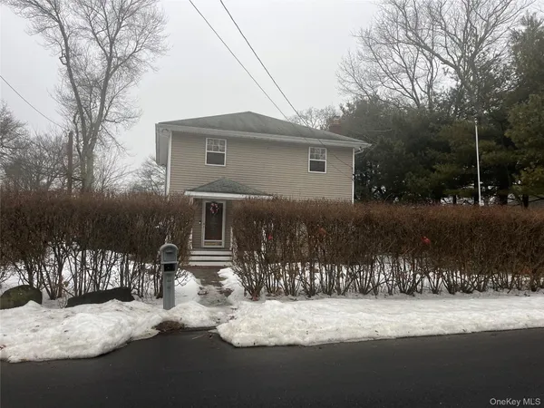 a front view of a house with yard and trees in the background