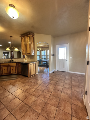 140 North 200 E Street Glenwood, UT 84730 - Photo 11 of 54 Kitchen featuring arched walkways, a textured ceiling, wood finish cabinets, dishwasher, and dark tile patterned floors