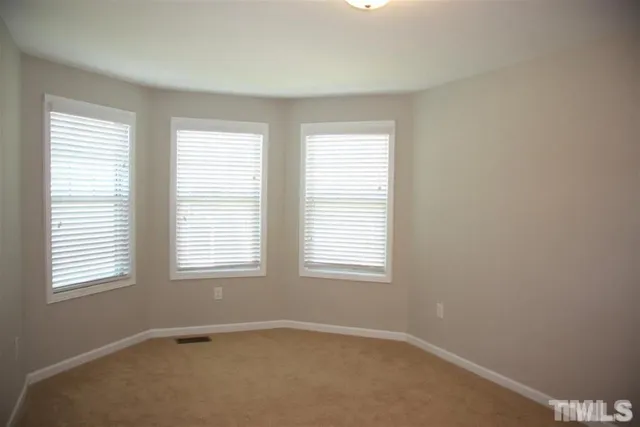 a view of an empty room with closet and a window