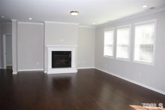an empty room with wooden floor fireplace and windows