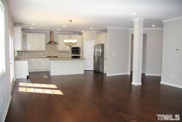 a kitchen with stainless steel appliances granite countertop a refrigerator a sink a stove and oven with wooden floor