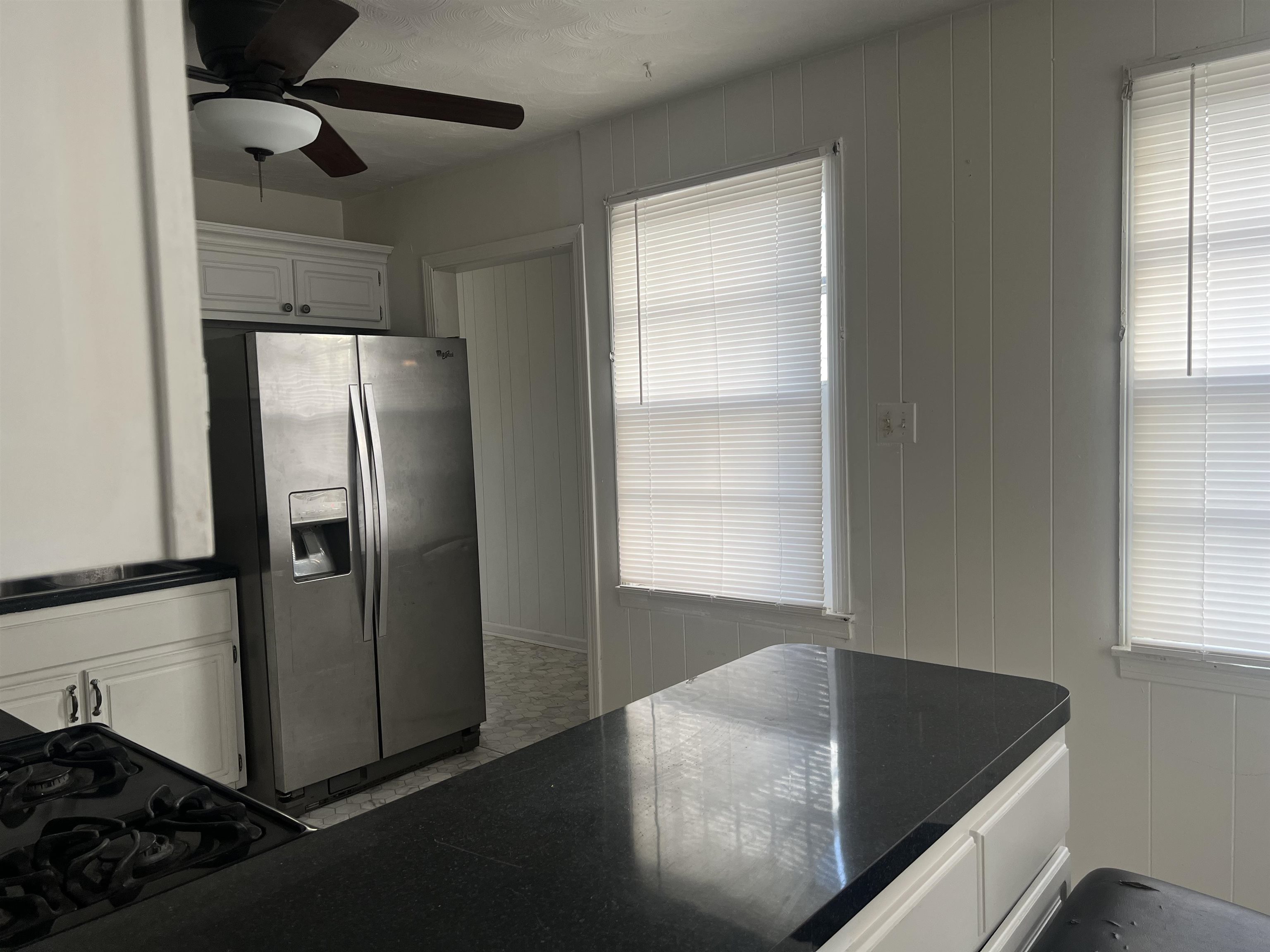 Kitchen with white cabinets, ceiling fan, and stainless steel fridge