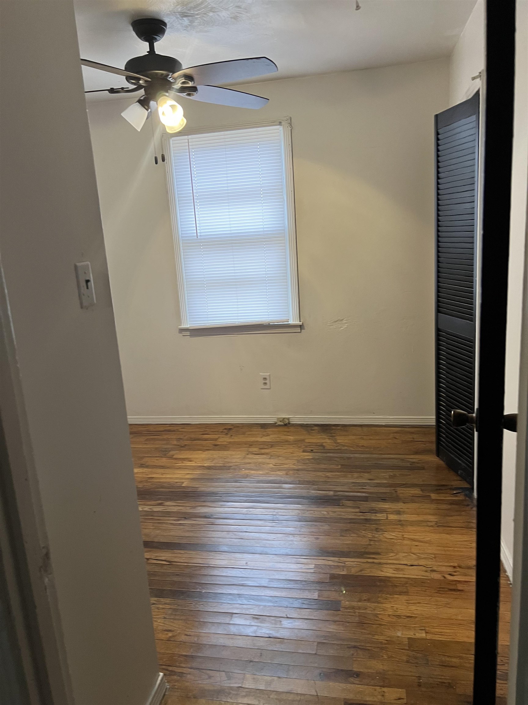 Unfurnished bedroom featuring ceiling fan and dark wood-type flooring
