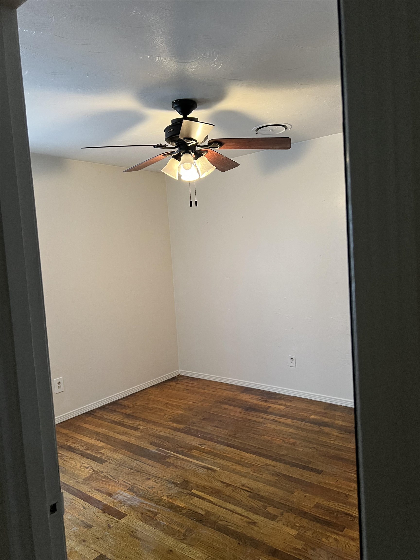 Unfurnished room featuring ceiling fan and dark wood-type flooring