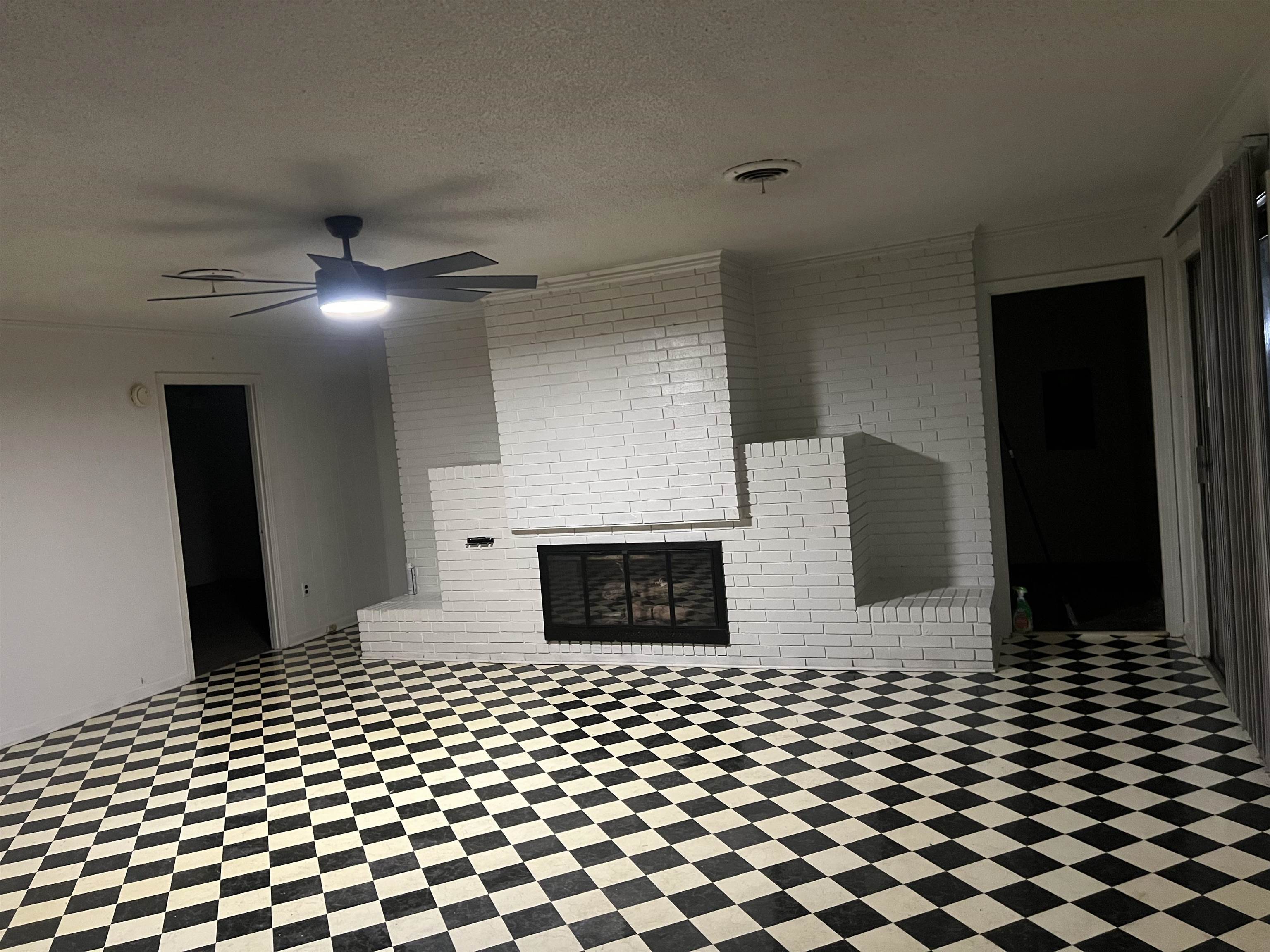 3548 Yokley Road Memphis, TN 38109 - Photo 10 of 16 Unfurnished living room featuring ceiling fan, a fireplace, brick wall, and a textured ceiling