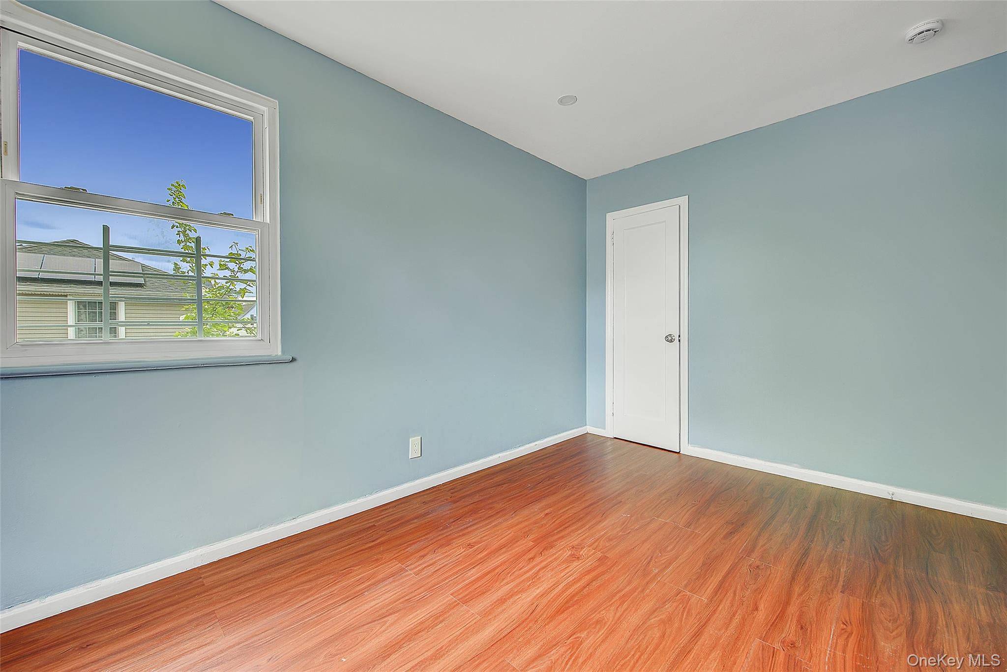 164-38 76th Road Queens, NY 11366 - Photo 25 of 44 an empty room with wooden floor and windows