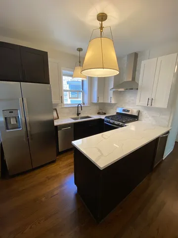 a kitchen with stainless steel appliances a sink a stove a refrigerator a sink a dining table and cabinets