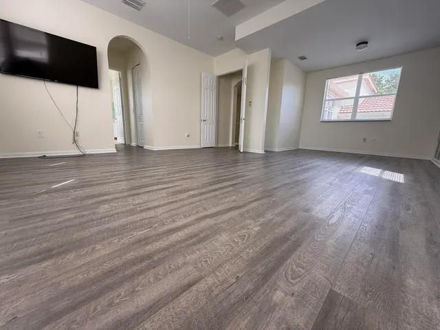an empty room with wooden floor and windows