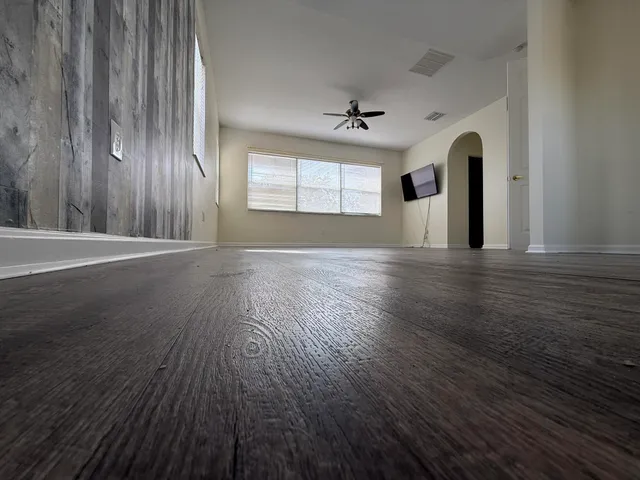 a view of empty room with wooden floor and fan