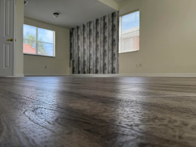 an empty room with wooden floor and windows