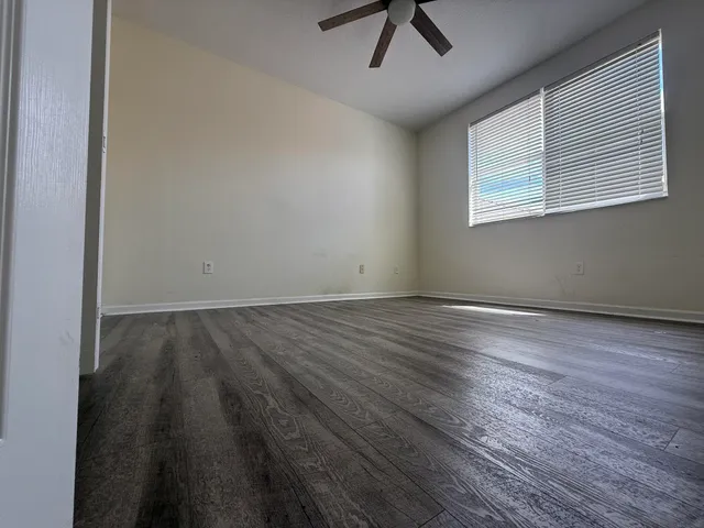 an empty room with wooden floor and windows