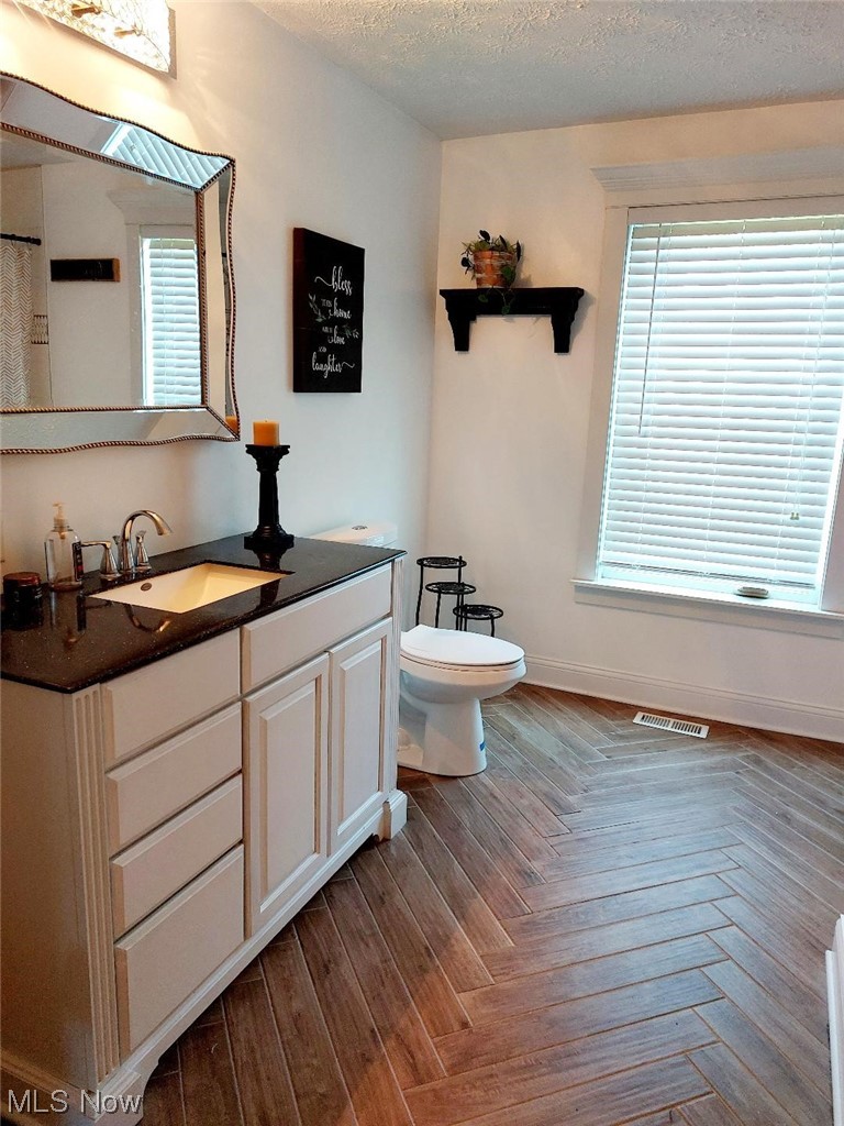 3061 Sandy Lake Road Ravenna, OH 44266 - Photo 11 of 15 Bathroom featuring parquet flooring, vanity, mirror, and a textured ceiling