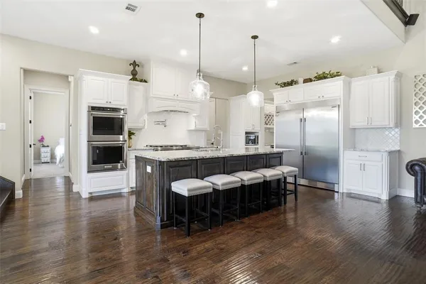 a kitchen with stainless steel appliances granite countertop a refrigerator a oven and a fireplace