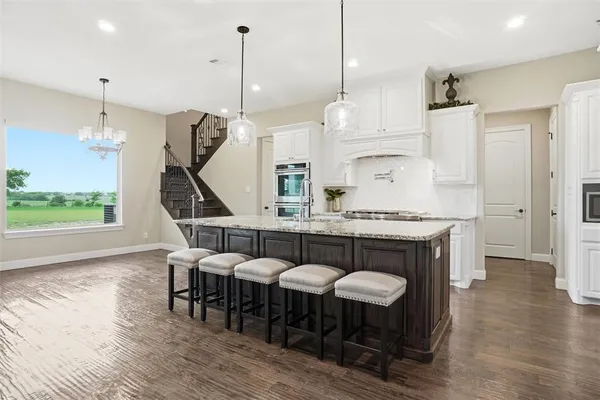 a open kitchen with stainless steel appliances granite countertop a table chairs and a wooden floor