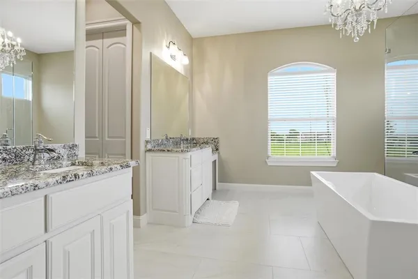a spacious bathroom with a double vanity sink a mirror and a bathtub