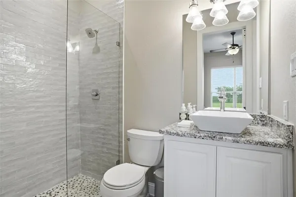 a bathroom with a granite countertop sink a toilet and shower