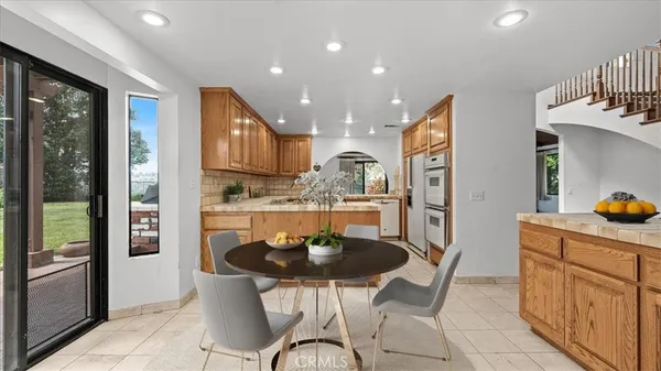 a kitchen with stainless steel appliances granite countertop a stove a refrigerator a kitchen island a dining table and chairs with wooden floor