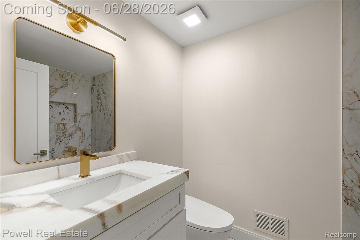 1447 Ravineview Court, Unit C12 Bloomfield Hills, MI 48304 - Photo 42 of 49 Vanity featuring a white stone countertop with integrated sink and a gold-finish faucet